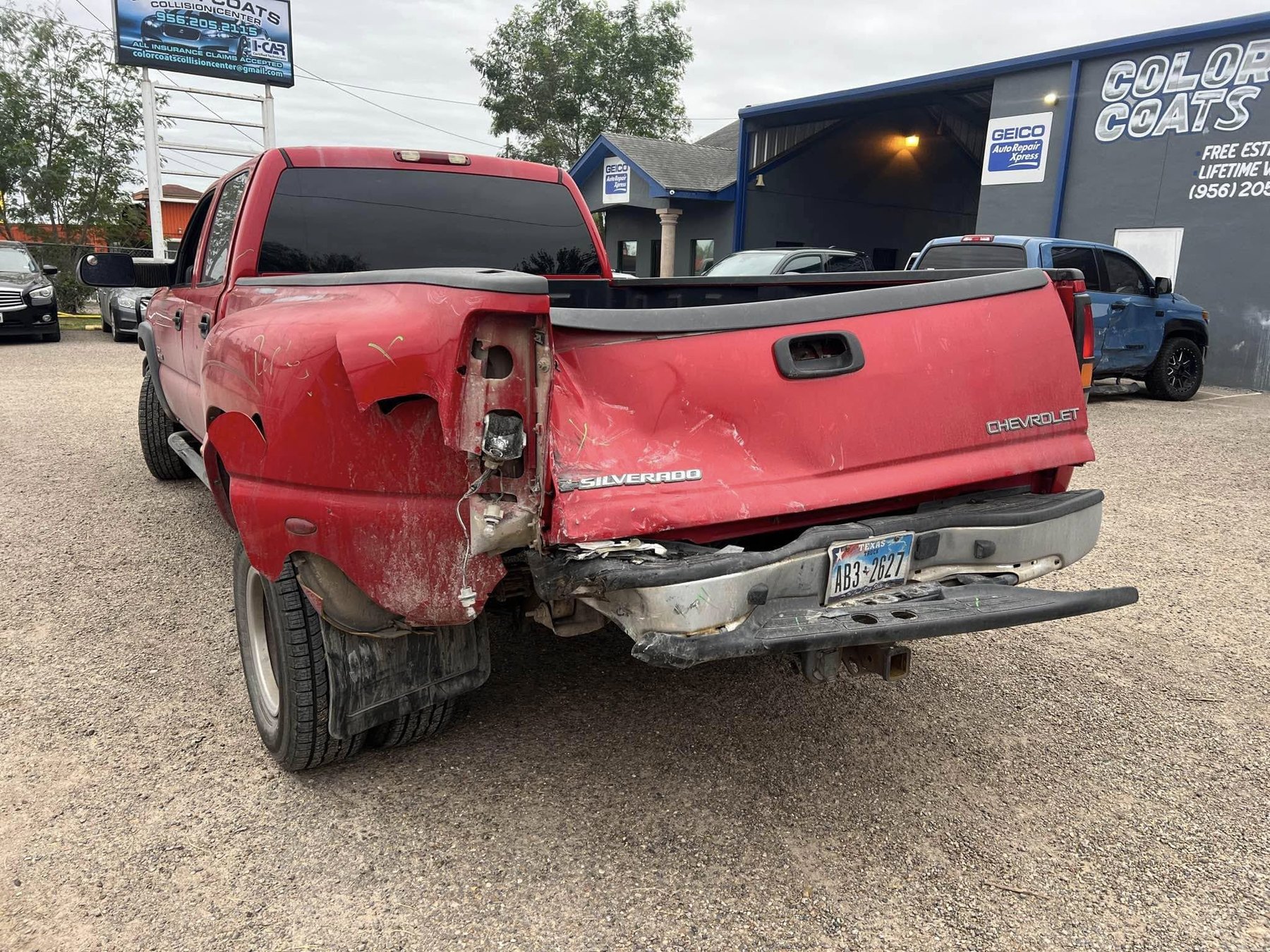 Red Chevrolet Silverado with damaged tailgate, bumper, and rear bedside before repair