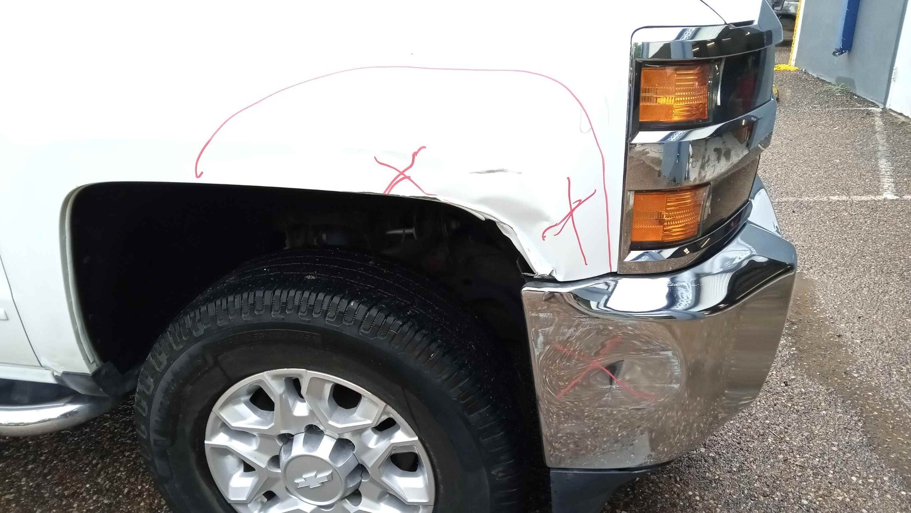White Chevrolet Silverado HD with damaged front fender and bumper before repair